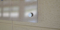 Thumbnail for Clear acrylic wall sign mounted with a silver standoff on a textured beige wall.