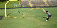 Thumbnail for Man in athletic wear exercising with yellow battle ropes on a green field.