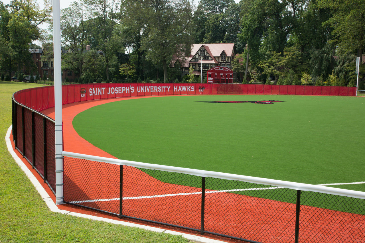 Red mesh baseball outfield fence windscreen on synthetic turf field at Saint Joseph's University Hawks