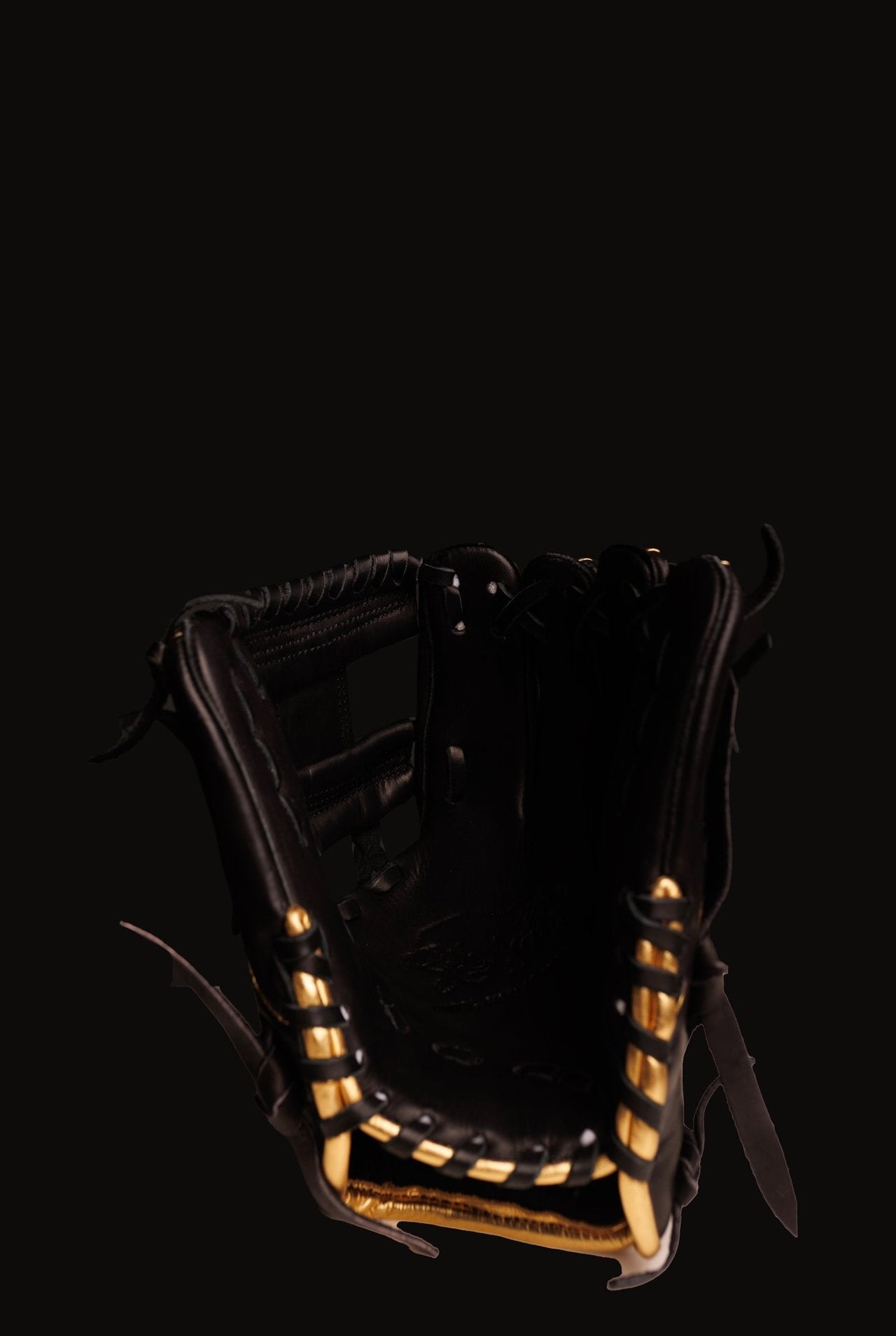 Black baseball glove with gold laces and trim, viewed from above against a dark background.