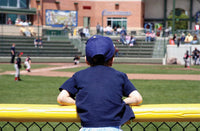 Thumbnail for Little league player leaning on yellow SafeFoam foam padding along an outfield fence top