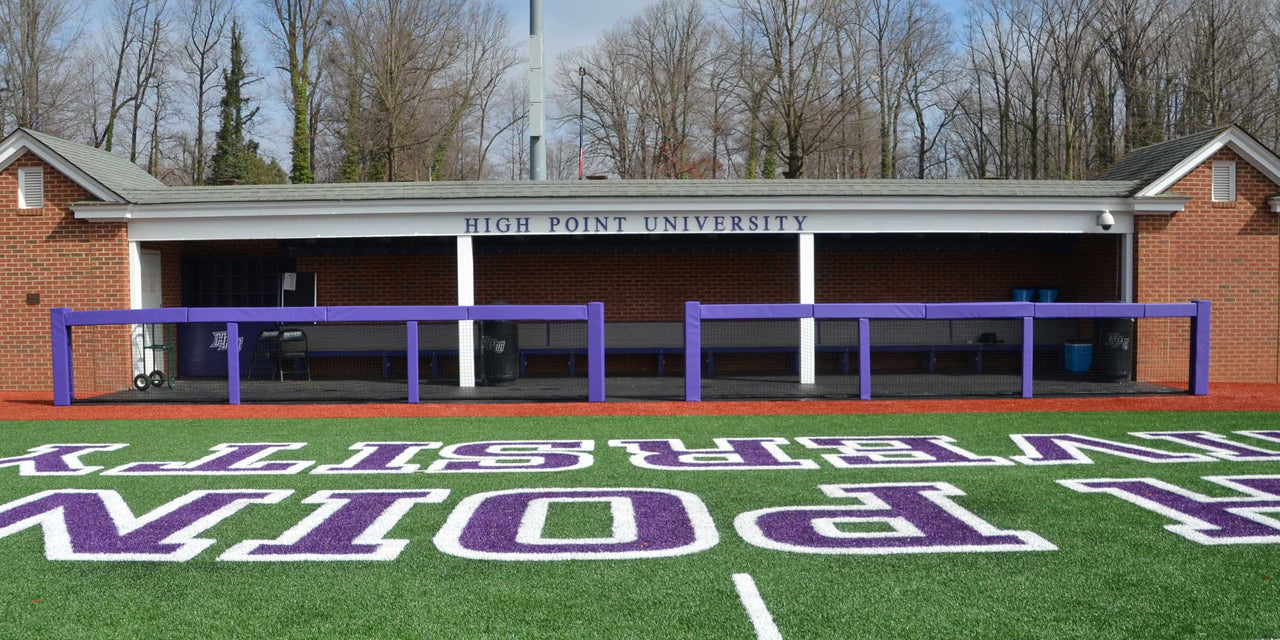 Purple square rail padding on two dugout rails in front of a brick dugout