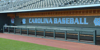 Thumbnail for Green square rail padding along a dugout below a Carolina Baseball wall