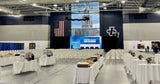 Gray GymGuard vinyl gym floor cover deployed full-court at John Carroll University, with rows of folding chairs and catering tables on the protected floor.