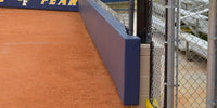 Thumbnail for Side view of navy L-shaped padding capping the top edge and face of a low backstop wall