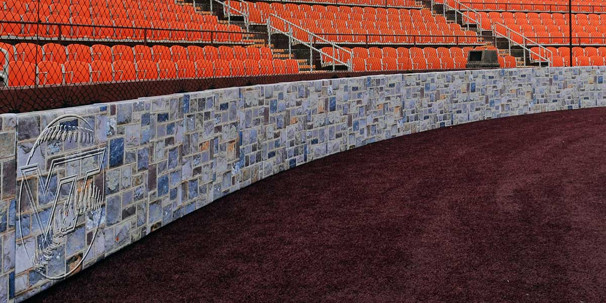 Backstop padding printed with a stone wall graphic curving behind home plate