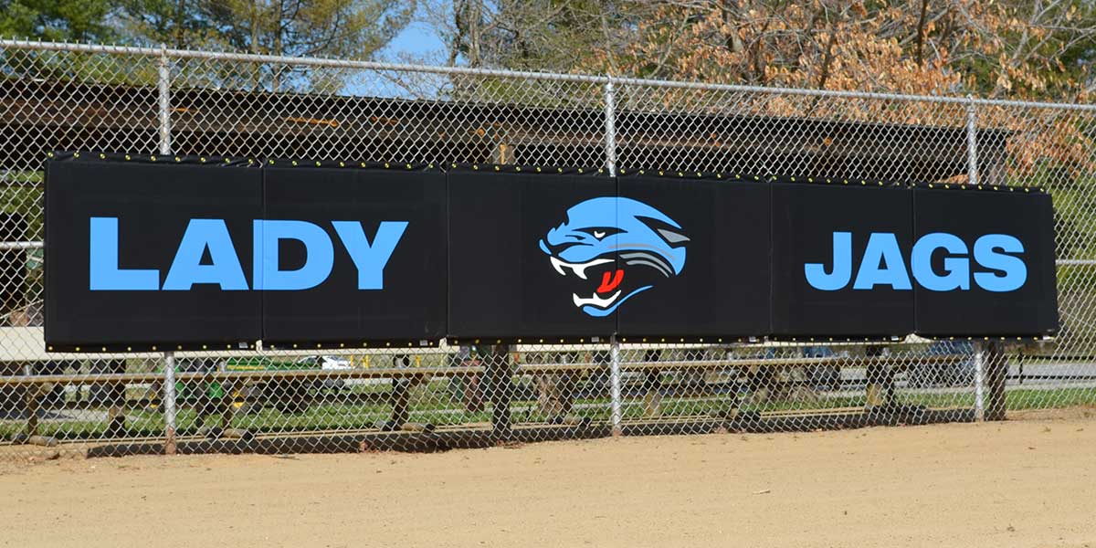 Black fence padding printed with Lady Jags and a jaguar logo hung on a chain link fence