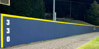 Thumbnail for Navy outfield wall padding with a yellow top edge and a 330 distance marker at a college baseball field