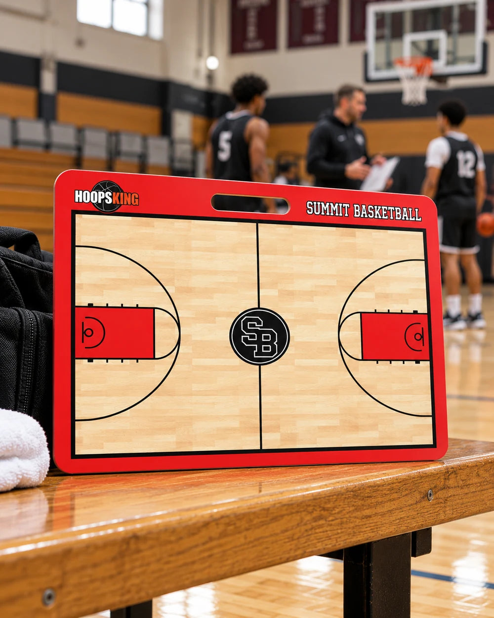 Custom red Summit Basketball 23 by 18 inch coaching board with centered carry handle on a gym sideline bench